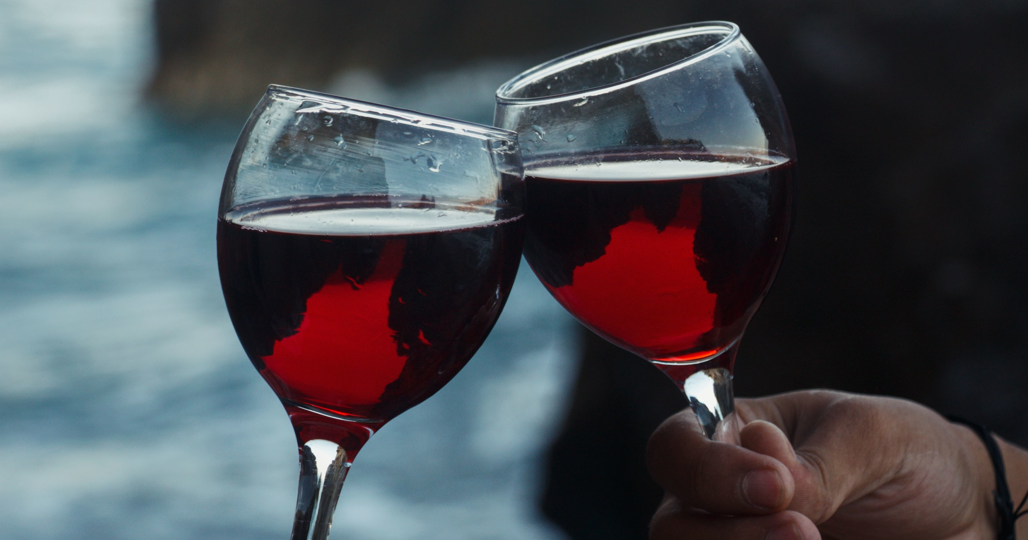 Two glasses of dry red wine on a rustic wooden table outdoors